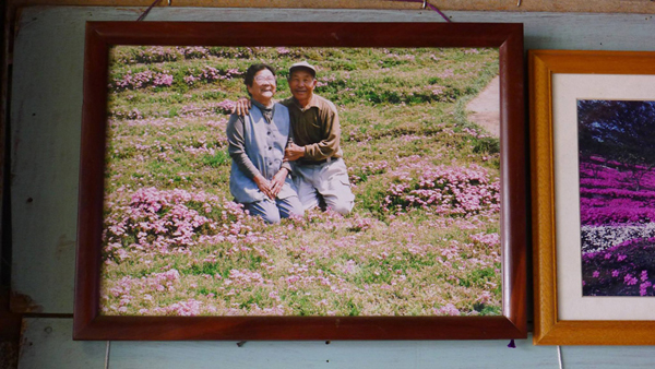 Cặp vợ chồng già chụp ảnh bên vườn hoa.