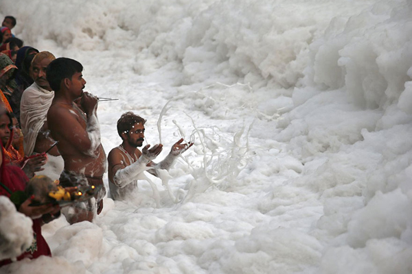 Nước thải công nghiệp và rác thải khiến dòng sông Yamuna ở New Delhi, Ấn Độ, bị ô nhiễm nặng nề sủi đầy bọt. Tuy nhiên, người dân địa phương vẫn tắm rửa và làm lễ cầu nguyện trên sông. Ảnh: businessinsider.in