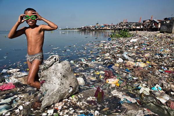 Cậu bé mưu sinh bằng cách lặn ngụp trong bãi rác bẩn thỉu mỗi ngày để nhặt nhạnh phế liệu tái chế. Ảnh: George Steinmetz.