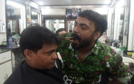 Thay vì dùng tay, Ansar ngậm kéo trong miệng của mình để cắt tóc cho khách hàng