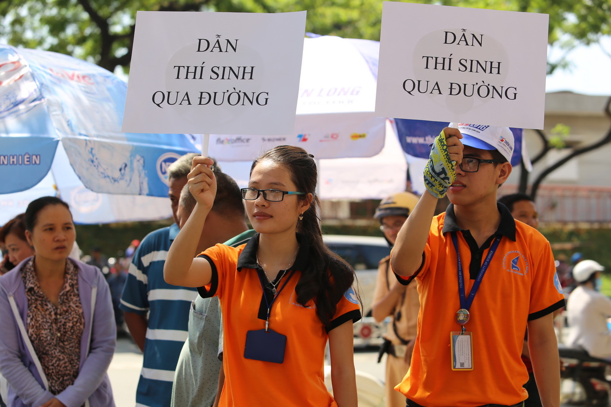 Hai sinh viên tình nguyện đang cầm bảng dẫn thí sinh qua đường tại HĐT trường KHTN, TP.HCM - Ảnh: NHƯ HÙNG