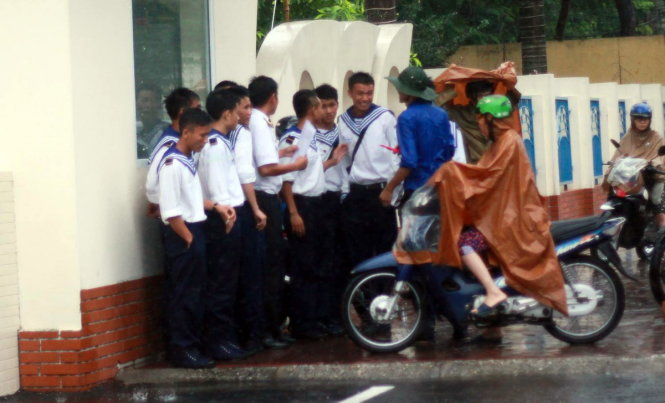 Sinh viên tình nguyện ở Quảng Ninh đội mưa để hướng dẫn cho thí sinh đến các điểm thi theo giấy báo - Ảnh: TIẾN THẮNG