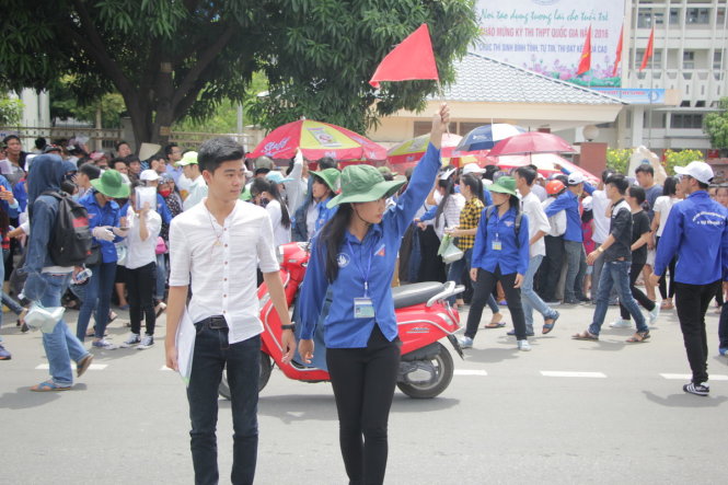 Một nữ tình nguyện viên ở Nghệ An trở thành người dẫn đường, giúp thí sinh yên tâm hơn khi qua đường sau giờ tan buổi thi môn Toán - Ảnh: DOÃN HÒA