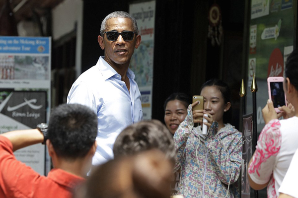 People take photos of U.S. President Barack Obama as he tours a shopping area near the Mekong River