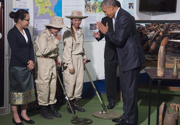 The president has pledged to spend $90million over the three years to help clear the unexploded bombs in Laos (pictured: he meets with ordinance detectors)