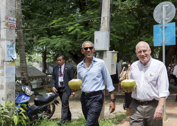Obama and US Ambassador to Laos Daniel Clune enjoyed a drink from a coconut as they walked along the Mekong River