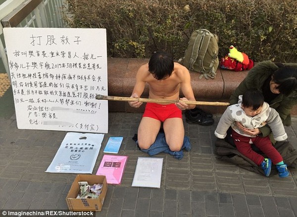 Fan Fugui quỳ trên đường, chỉ mặc quần lót trong thời tiết giá lạnh. Bên cạnh là vợ và con trai