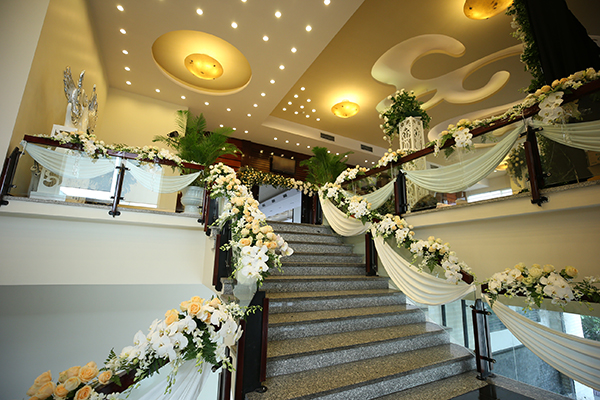 [Caption]Ngay từ cầu thang sảnh tầng 1 là đường dẫn hoa với nến lung linh , cầu thang lối lên sảnh chính được phủ kín hoa tông màu trắng kem ấm cúng và sang trọng.