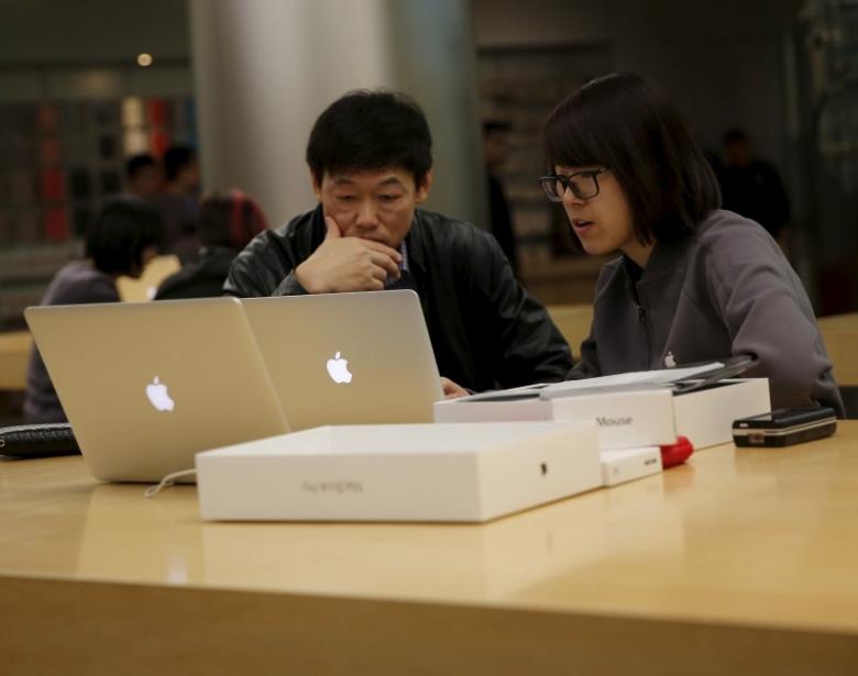Một nhân viên nữ tại cửa hàng Apple tại Bắc Kinh hướng dẫn khách hàng - Ảnh: Reuters